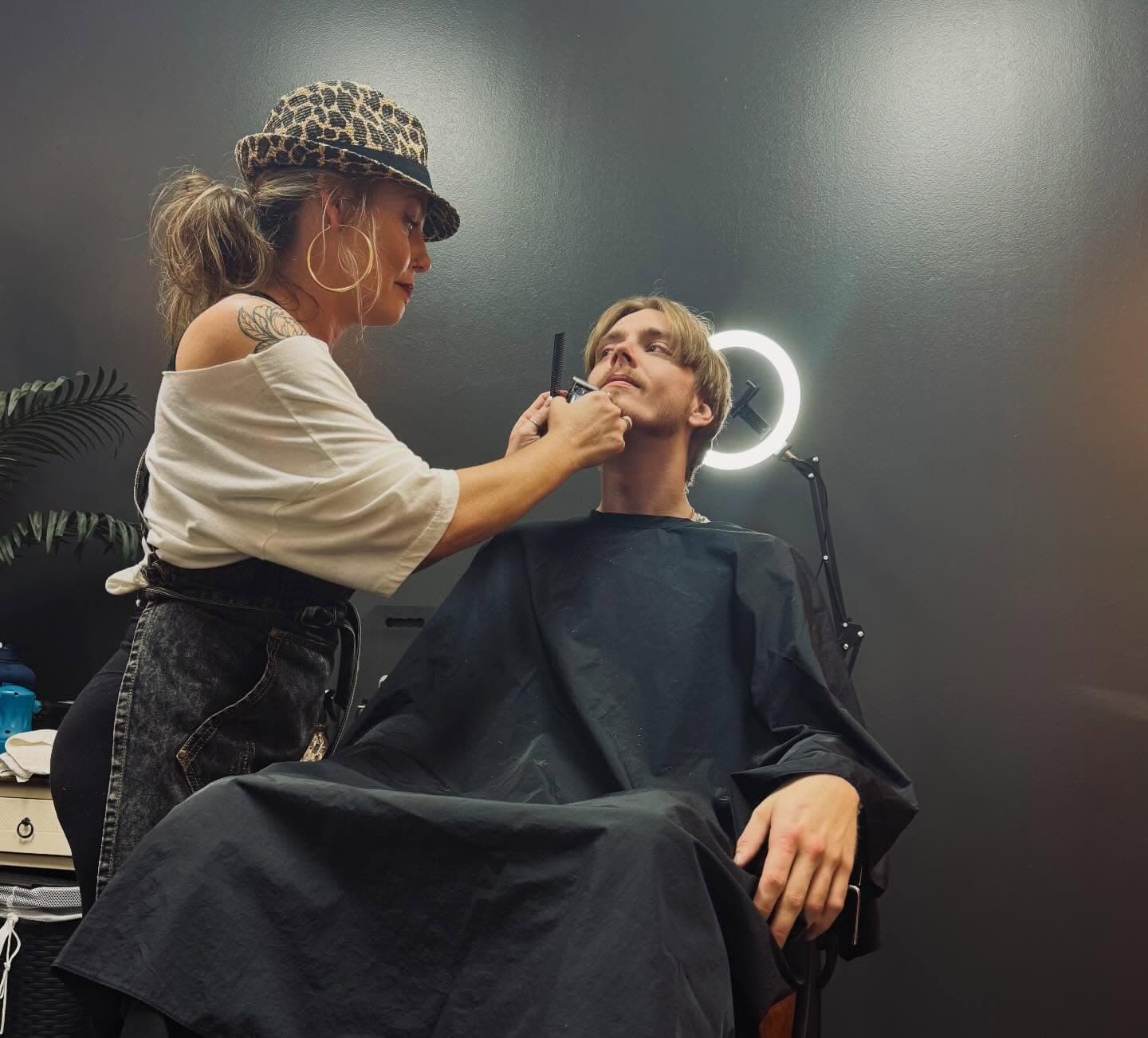 Sara Jane trimming a client's beard in her shop